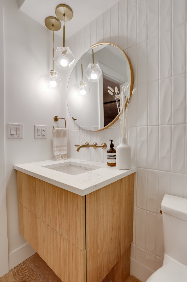 Inspiration for a medium sized scandi cloakroom in Vancouver with flat-panel cabinets, medium wood cabinets, a one-piece toilet, white tiles, ceramic tiles, white walls, medium hardwood flooring, a submerged sink, quartz worktops, brown floors, white worktops and a floating vanity unit.