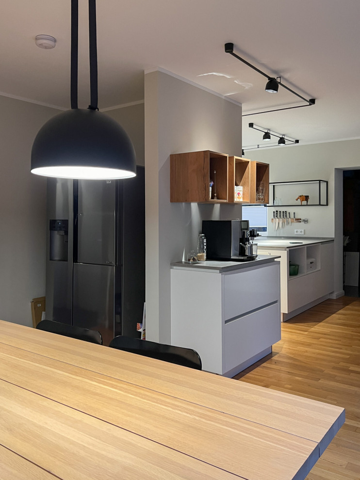 Offene, Geräumige Industrial Küche in U-Form mit Waschbecken, flächenbündigen Schrankfronten, weißen Schränken, Mineralwerkstoff-Arbeitsplatte, Küchenrückwand in Weiß, Rückwand aus Quarzwerkstein, weißen Elektrogeräten, hellem Holzboden, Halbinsel, braunem Boden, grauer Arbeitsplatte und Tapetendecke in Hamburg