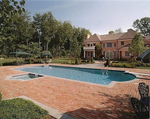 Design ideas for a large traditional backyard custom-shaped lap pool in New York with brick pavers and a hot tub.