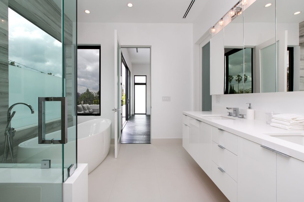 Design ideas for a mid-sized contemporary master bathroom in Los Angeles with flat-panel cabinets, white cabinets, a freestanding tub, a corner shower, white walls, an undermount sink, solid surface benchtops and ceramic floors.