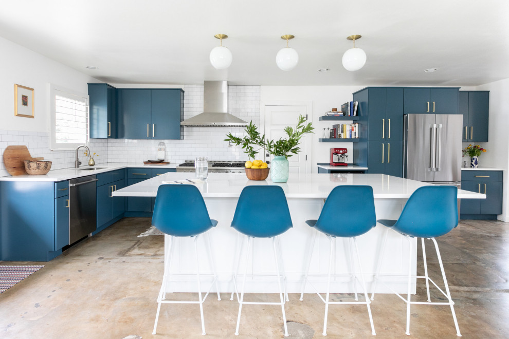Mid-sized contemporary l-shaped open plan kitchen in Austin with an undermount sink, flat-panel cabinets, blue cabinets, quartz benchtops, white splashback, subway tile splashback, stainless steel appliances, concrete floors, with island, grey floor and white benchtop.