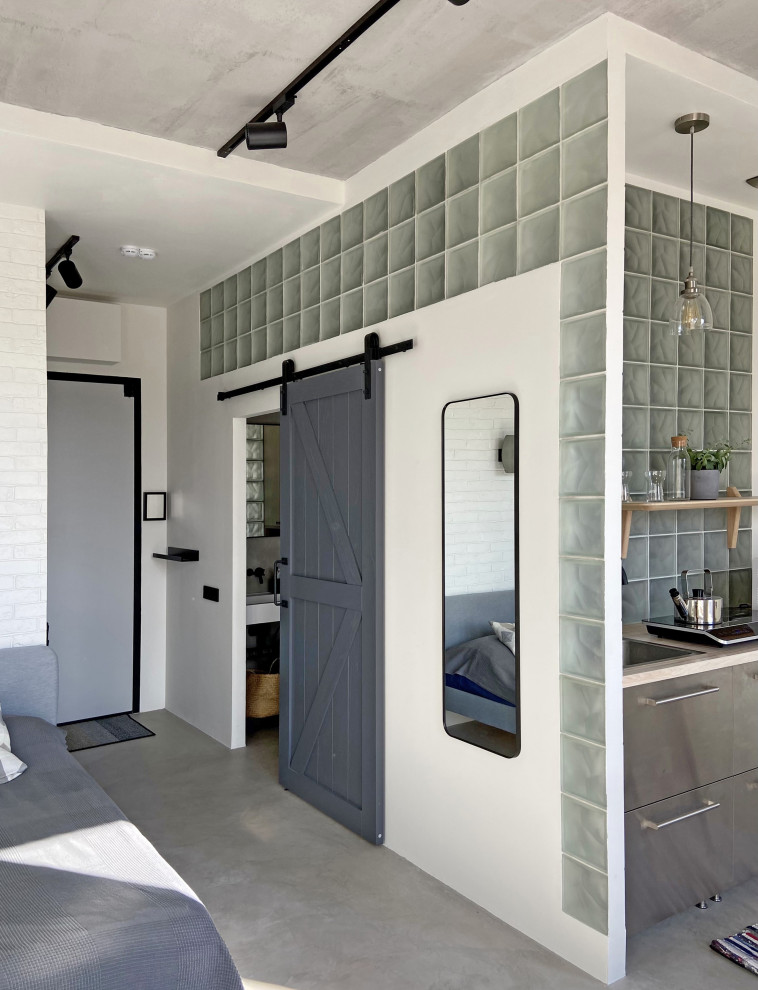 This is an example of an industrial entryway in Moscow with white walls, concrete floors, a sliding front door, a gray front door and grey floor.