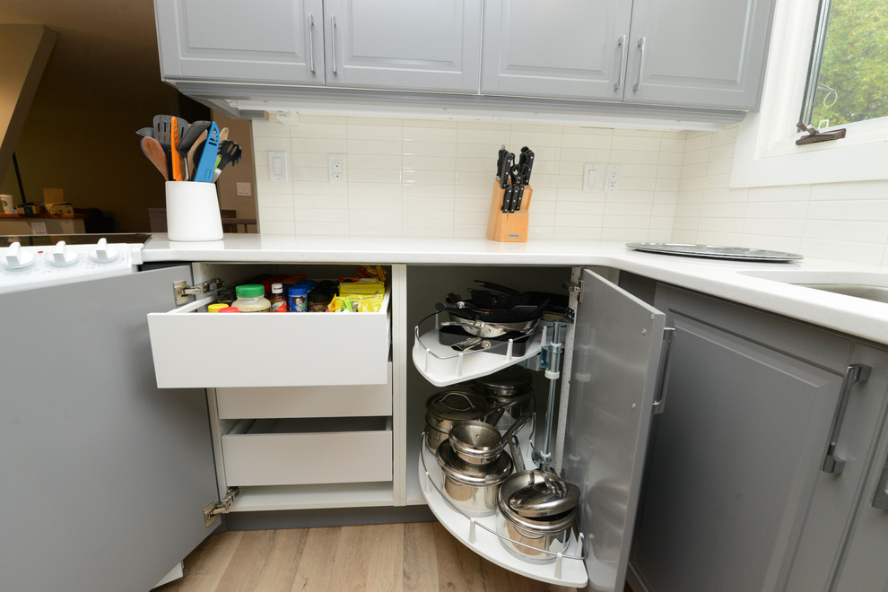 Enclosed kitchen - small traditional light wood floor and beige floor enclosed kitchen idea with an undermount sink, raised-panel cabinets, gray cabinets, quartz countertops, white backsplash, ceramic backsplash, white appliances, no island and white countertops