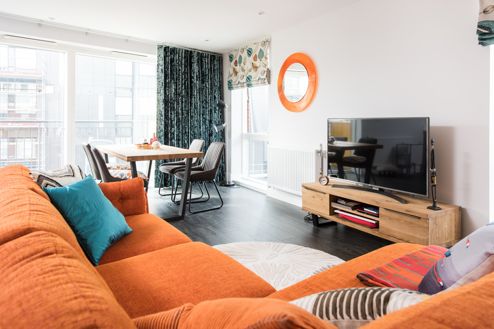 Photo of a medium sized contemporary grey and teal enclosed living room with grey walls, dark hardwood flooring, no fireplace, a freestanding tv and brown floors.