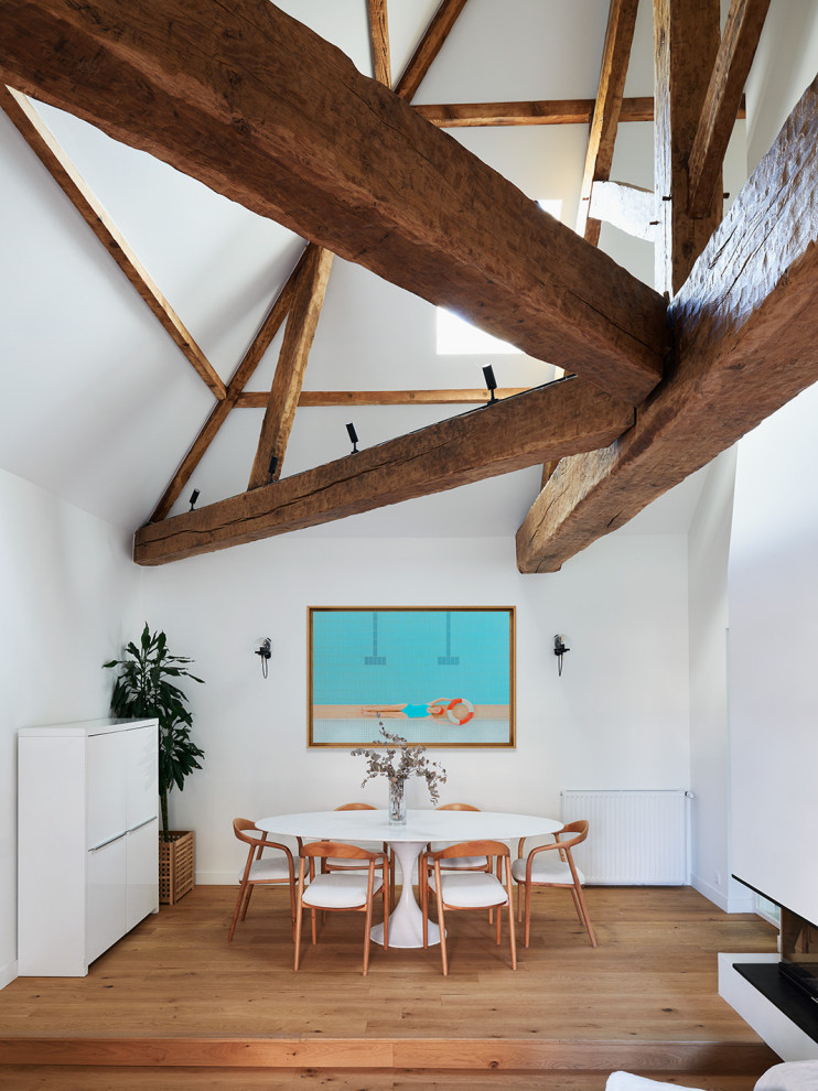 Exemple d'une grande salle à manger tendance avec un mur bleu, parquet clair, une cheminée d'angle, un manteau de cheminée en plâtre, un sol marron, poutres apparentes et verrière.