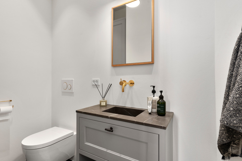 Exemple d'un WC suspendu chic de taille moyenne avec un placard avec porte à panneau surélevé, des portes de placard grises, un mur blanc, un sol en marbre, un lavabo intégré, un plan de toilette en marbre, un sol marron et meuble-lavabo suspendu.