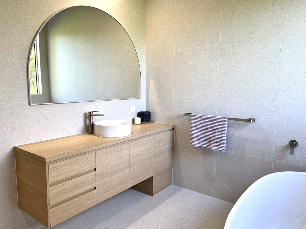 This is an example of a large contemporary family bathroom in Sunshine Coast with flat-panel cabinets, light wood cabinets, a freestanding bath, a walk-in shower, a one-piece toilet, grey tiles, a vessel sink, laminate worktops, grey floors, an open shower, a wall niche, a single sink and a built in vanity unit.