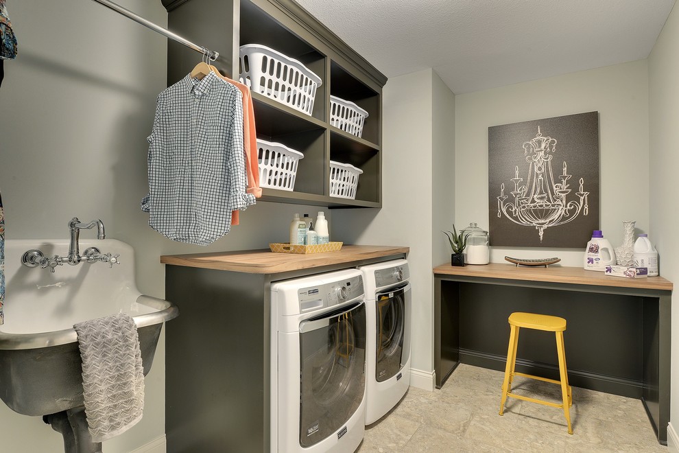 This is an example of a large transitional l-shaped laundry room in Minneapolis with an utility sink, open cabinets, grey cabinets, laminate benchtops, grey walls, ceramic floors, a side-by-side washer and dryer and grey floor.