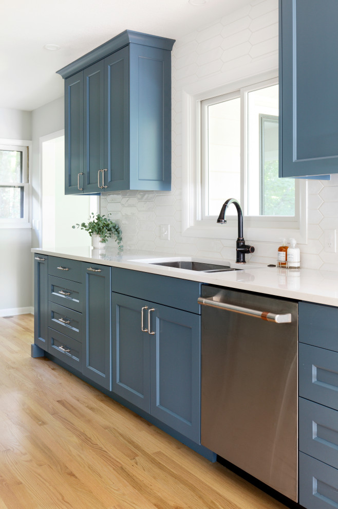 Inspiration for a mid-sized transitional galley eat-in kitchen in Portland with an undermount sink, recessed-panel cabinets, blue cabinets, quartz benchtops, white splashback, cement tile splashback, stainless steel appliances, light hardwood floors, no island and white benchtop.