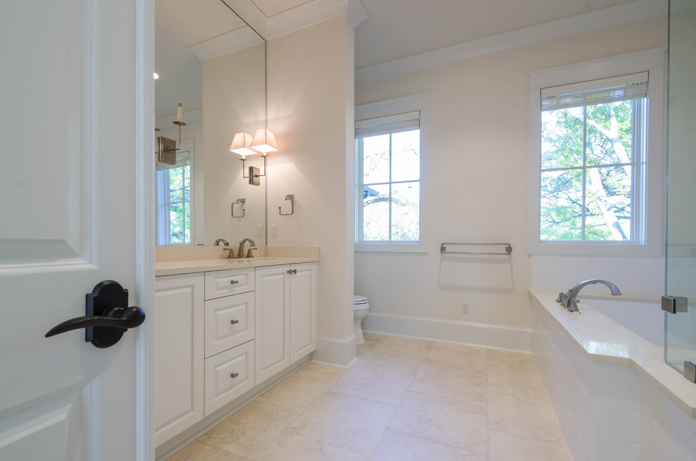 Photo of a mid-sized traditional master bathroom in New Orleans with beaded inset cabinets, white cabinets, an undermount tub, yellow walls, travertine floors, an undermount sink, engineered quartz benchtops and a corner shower.