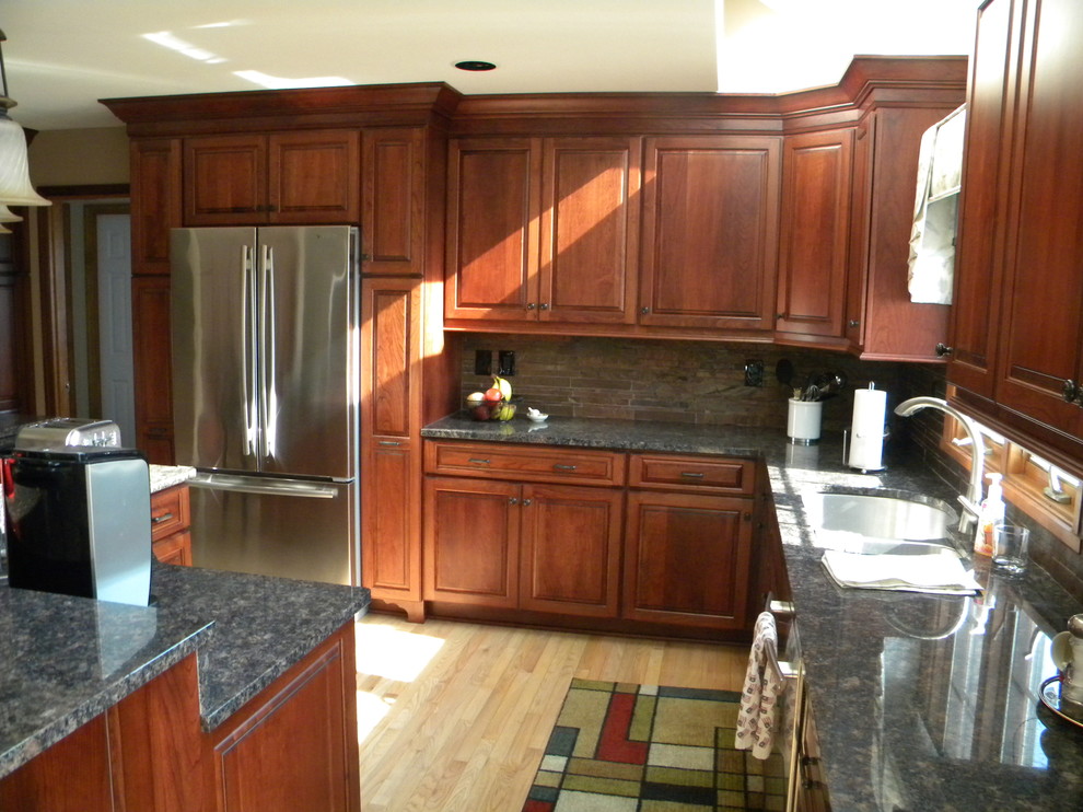 Example of a mid-sized transitional u-shaped light wood floor eat-in kitchen design with an undermount sink, raised-panel cabinets, medium tone wood cabinets, granite countertops, multicolored backsplash, stone tile backsplash, stainless steel appliances and an island