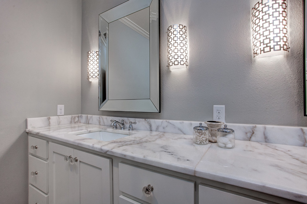 Inspiration for a mid-sized transitional master bathroom in Little Rock with shaker cabinets, white cabinets, a drop-in tub, an open shower, a one-piece toilet, gray tile, white tile, stone tile, grey walls, ceramic floors, a drop-in sink and solid surface benchtops.