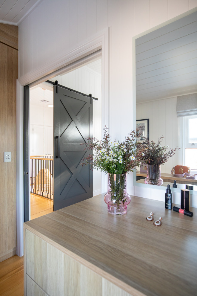 Idee per una cabina armadio unisex chic con ante lisce, ante in legno chiaro, pavimento in legno massello medio, pavimento marrone e soffitto in perlinato