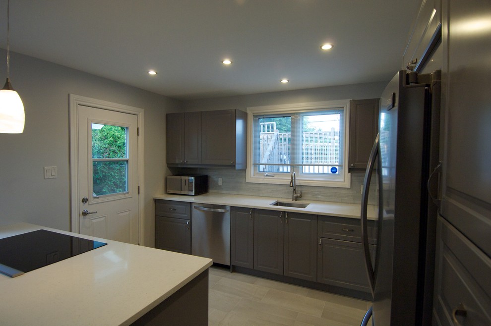 Inspiration for a mid-sized contemporary l-shaped porcelain tile and gray floor eat-in kitchen remodel in Ottawa with a single-bowl sink, raised-panel cabinets, gray cabinets, quartz countertops, gray backsplash, glass sheet backsplash, stainless steel appliances and a peninsula