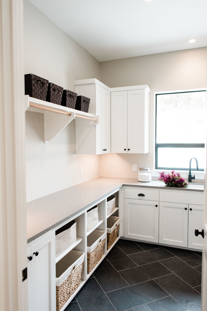 Inspiration for a mid-sized transitional l-shaped utility room in Austin with an undermount sink, shaker cabinets, white cabinets, quartzite benchtops, grey walls, slate floors, a side-by-side washer and dryer, black floor and grey benchtop.