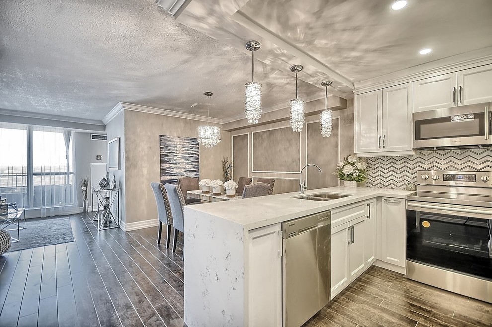 Open concept kitchen - mid-sized transitional u-shaped medium tone wood floor and brown floor open concept kitchen idea in Toronto with an undermount sink, recessed-panel cabinets, white cabinets, quartz countertops, gray backsplash, marble backsplash, stainless steel appliances and a peninsula