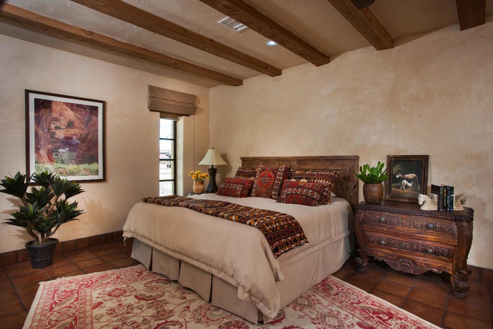 This is an example of a mid-sized master bedroom in Phoenix with beige walls, terra-cotta floors and brown floor.