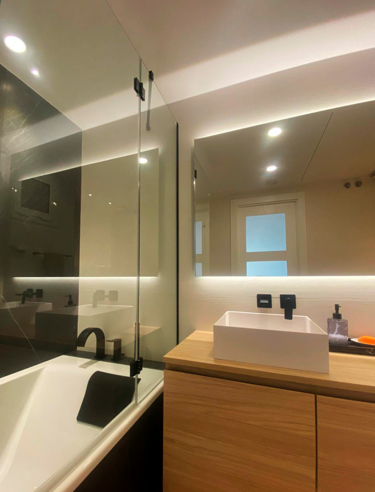 Foto på ett mellanstort funkis en-suite badrum, med vita skåp, ett badkar i en alkov, en vägghängd toalettstol, beige kakel, keramikplattor, svarta väggar, laminatgolv, ett fristående handfat, träbänkskiva och dusch med gångjärnsdörr