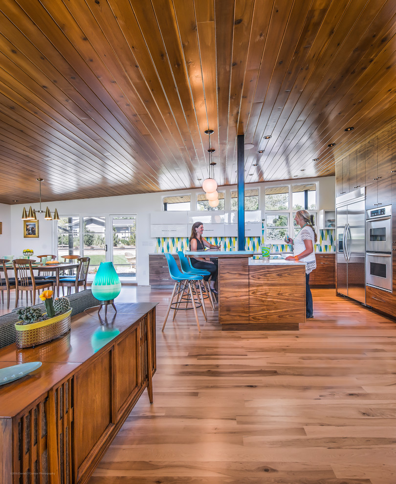 Photo of a midcentury kitchen in Denver with a drop-in sink, flat-panel cabinets, white cabinets, granite benchtops, multi-coloured splashback, ceramic splashback, stainless steel appliances, light hardwood floors, with island and turquoise benchtop.