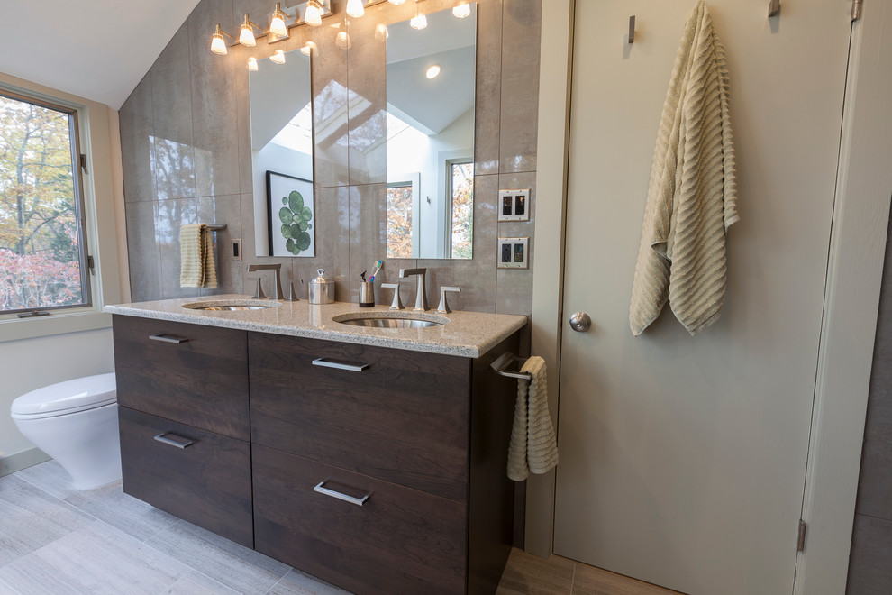 Large modern master bathroom in New York with flat-panel cabinets, brown cabinets, a freestanding tub, a corner shower, a two-piece toilet, gray tile, porcelain tile, grey walls, travertine floors, an undermount sink, recycled glass benchtops, grey floor and a hinged shower door.