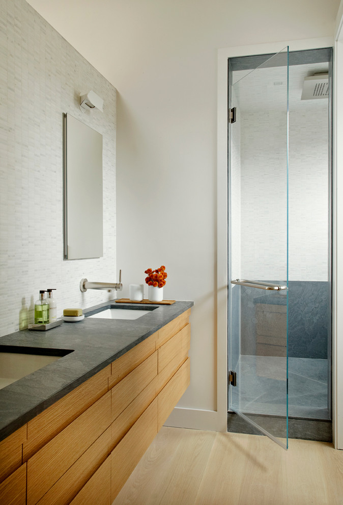 This is an example of a contemporary bathroom in New York with flat-panel cabinets, light wood cabinets, an alcove shower and white tile.