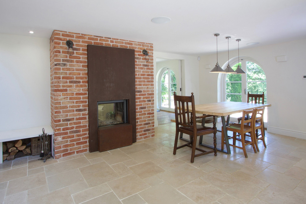 Inspiration for a large country kitchen/dining combo in Surrey with white walls, porcelain floors, a two-sided fireplace, a brick fireplace surround and beige floor.