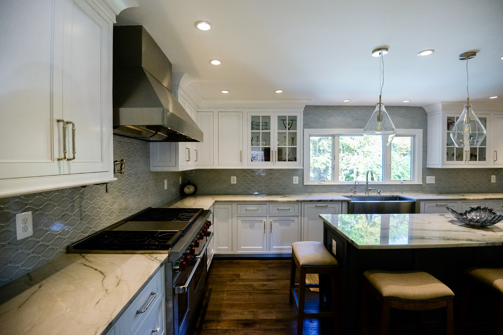 Eat-in kitchen - large transitional u-shaped medium tone wood floor and brown floor eat-in kitchen idea in DC Metro with a farmhouse sink, recessed-panel cabinets, white cabinets, marble countertops, stainless steel appliances, an island, gray backsplash and porcelain backsplash