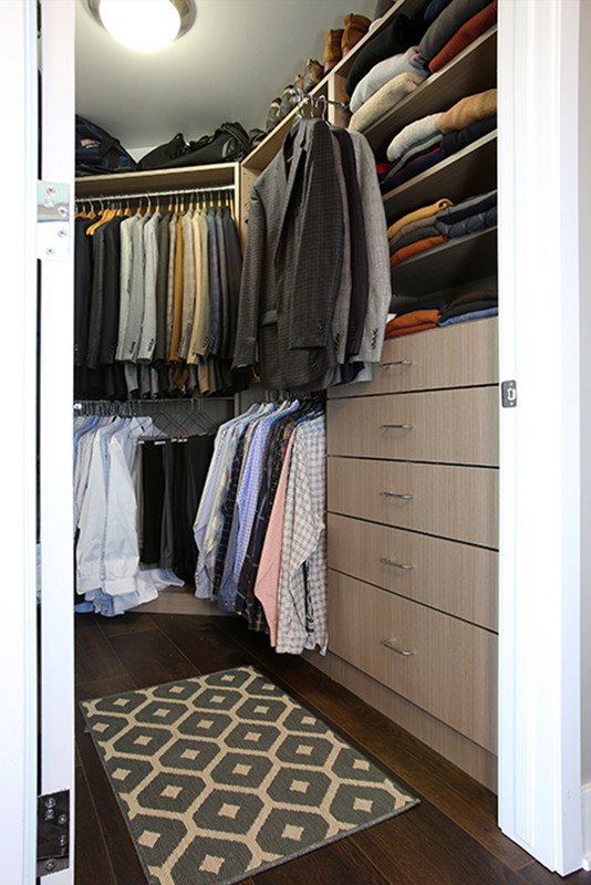 Inspiration for a mid-sized modern men's walk-in wardrobe in Grand Rapids with flat-panel cabinets, light wood cabinets, dark hardwood floors and brown floor.