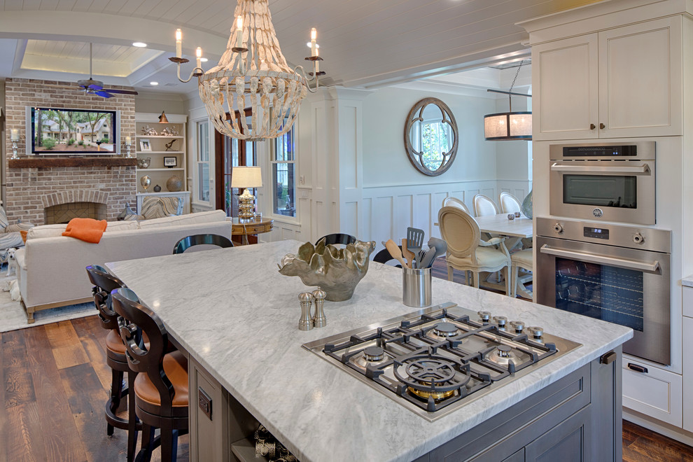 This is an example of a mid-sized country l-shaped eat-in kitchen in Grand Rapids with a double-bowl sink, recessed-panel cabinets, white cabinets, marble benchtops, stainless steel appliances, dark hardwood floors and with island.