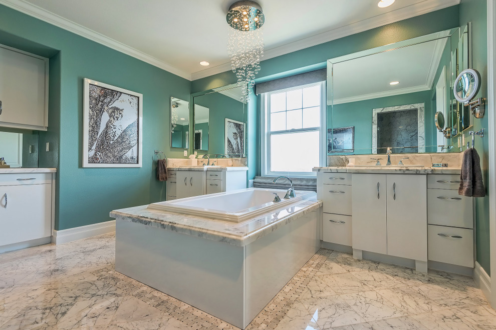 Photo of a large contemporary master bathroom in Los Angeles with flat-panel cabinets, white cabinets, a drop-in tub, an alcove shower, blue walls, marble floors, a drop-in sink, marble benchtops, white floor, a hinged shower door, white benchtops, an enclosed toilet, a double vanity and a built-in vanity.