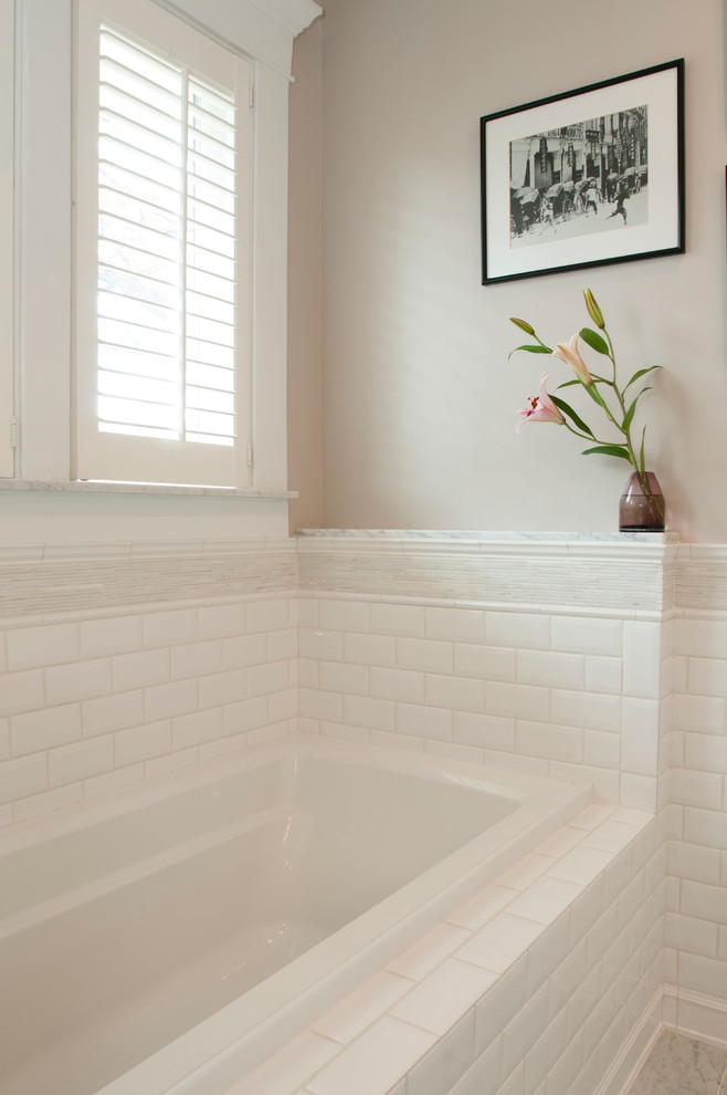 Design ideas for a mid-sized traditional master bathroom in New York with an undermount sink, raised-panel cabinets, white cabinets, marble benchtops, a corner shower, a wall-mount toilet, white tile, subway tile, beige walls, an undermount tub and marble floors.