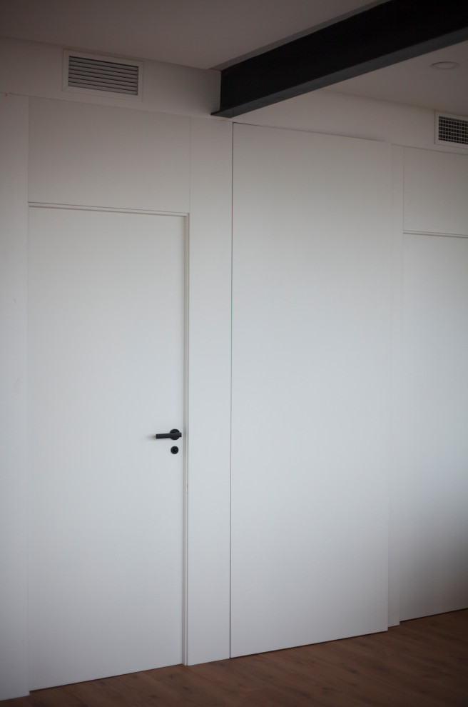 Exempel på ett mellanstort modernt loftrum, med vita väggar, laminatgolv och brunt golv