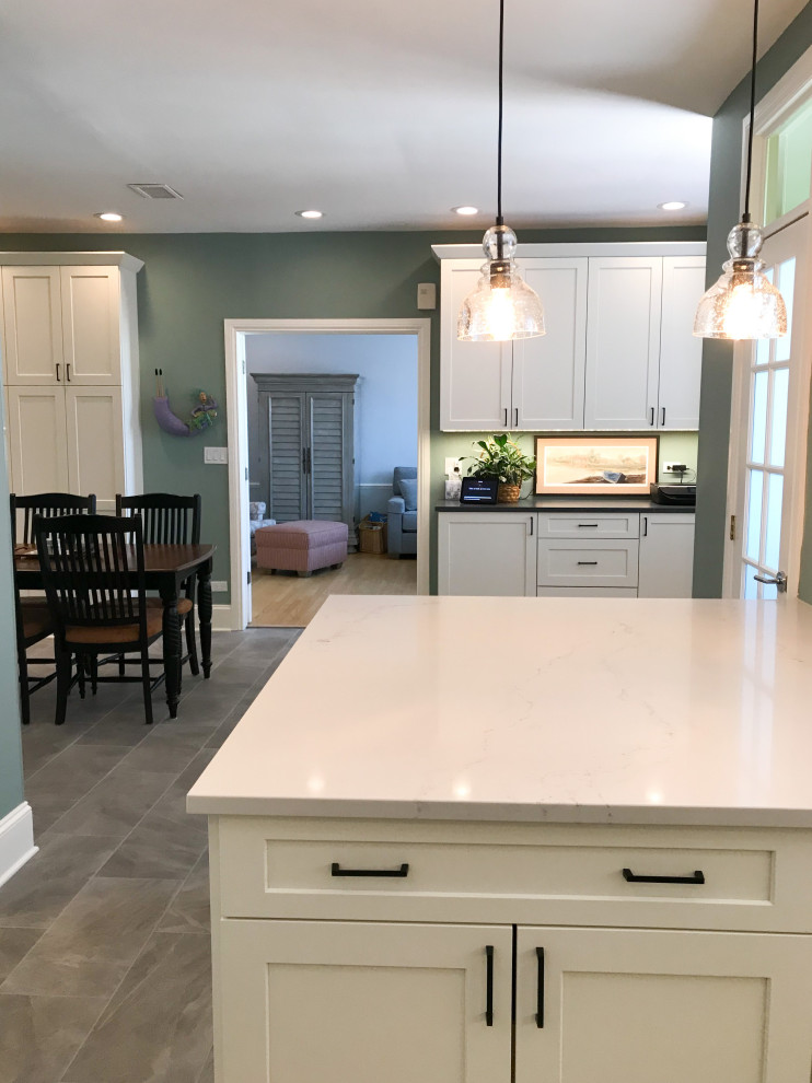 Photo of a mid-sized transitional l-shaped eat-in kitchen in Chicago with an undermount sink, shaker cabinets, white cabinets, blue splashback, glass sheet splashback, stainless steel appliances, porcelain floors, a peninsula, grey floor and white benchtop.