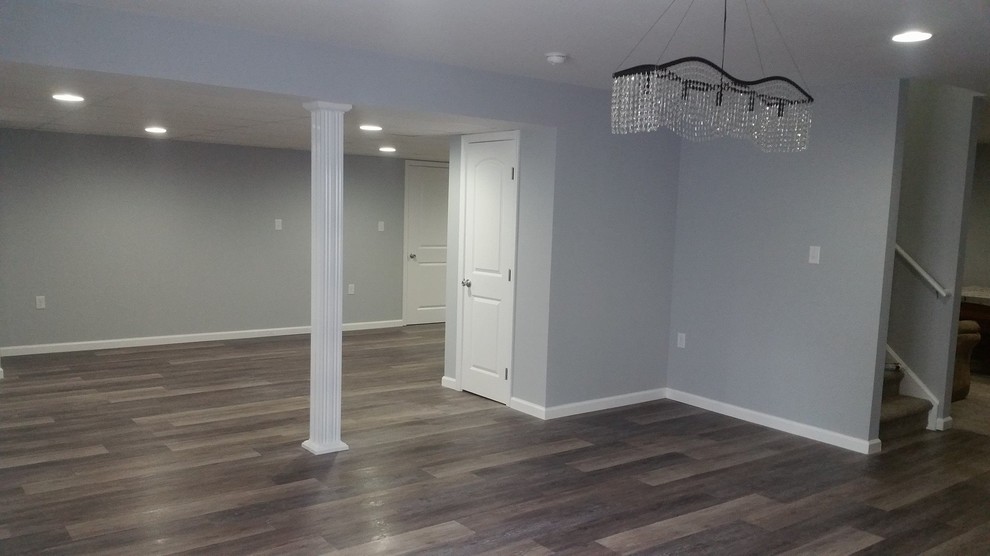 Photo of a large transitional fully buried basement in Philadelphia with grey walls, medium hardwood floors, no fireplace and brown floor.