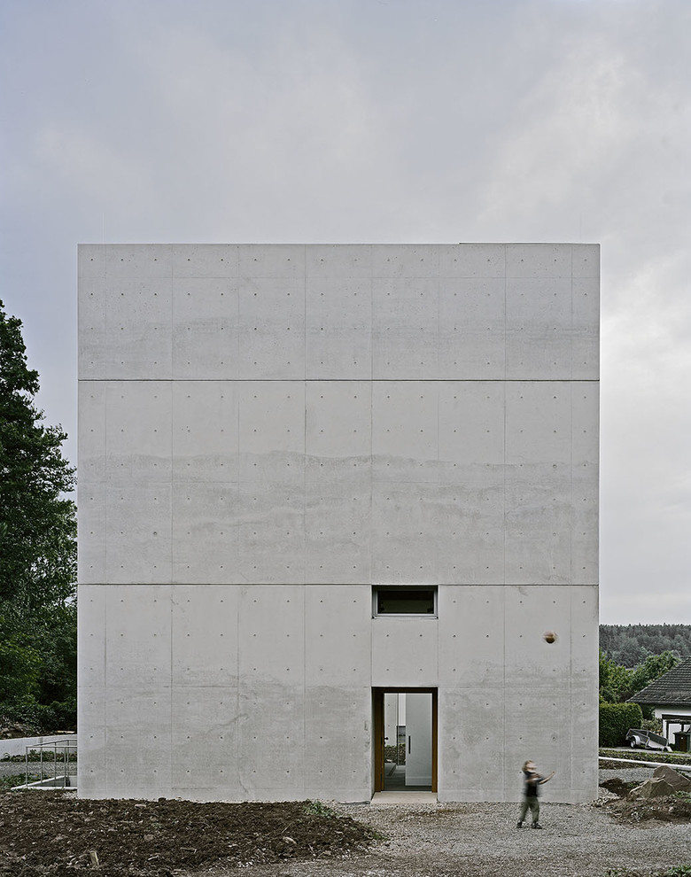 Mid-sized modern three-storey concrete grey house exterior in Stuttgart with a flat roof.