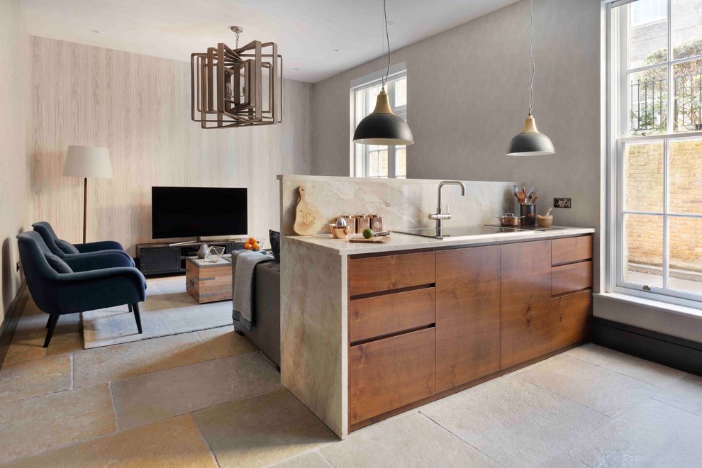 This is an example of a small contemporary galley open plan kitchen in London with an integrated sink, flat-panel cabinets, dark wood cabinets, marble benchtops, beige splashback, marble splashback, panelled appliances, limestone floors, with island and grey floor.