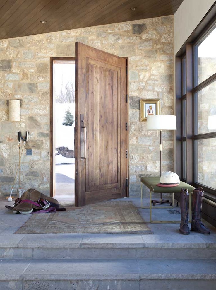 This is an example of a mid-sized country entryway in Denver with a single front door and a medium wood front door.