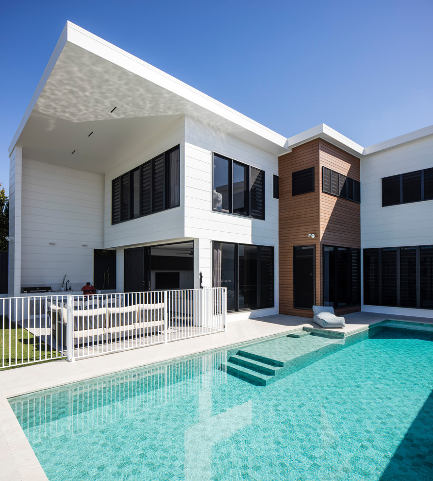 This is an example of a large midcentury backyard rectangular lap pool in Brisbane with tile.