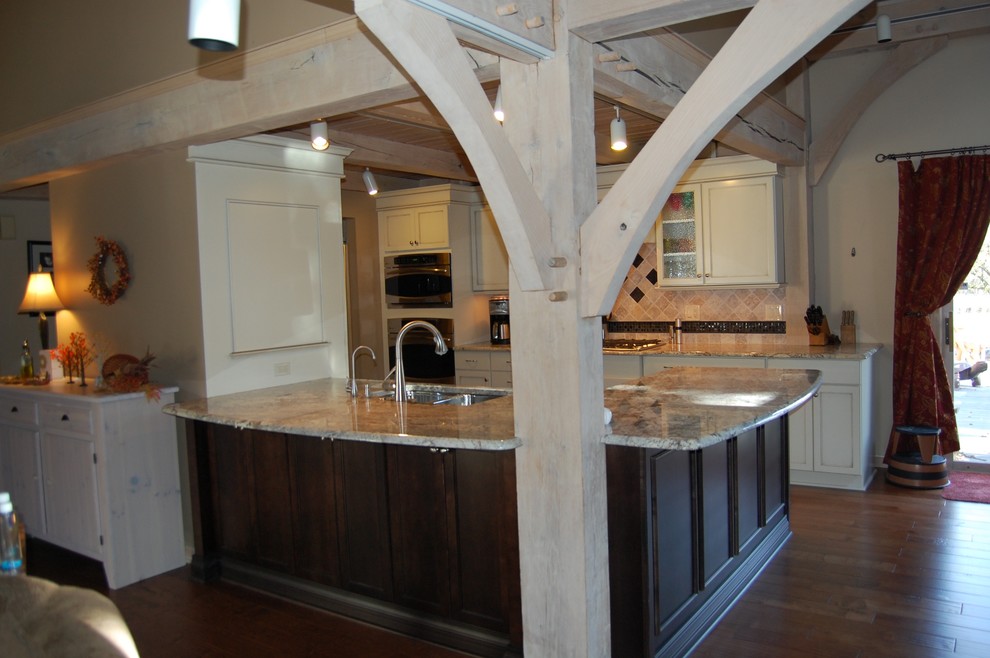 Mid-sized transitional u-shaped medium tone wood floor open concept kitchen photo in Chicago with an undermount sink, flat-panel cabinets, dark wood cabinets, granite countertops, beige backsplash, stone tile backsplash, stainless steel appliances and a peninsula