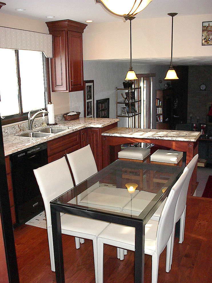 Small transitional u-shaped dark wood floor enclosed kitchen photo with an undermount sink, raised-panel cabinets, dark wood cabinets, granite countertops, black appliances and a peninsula