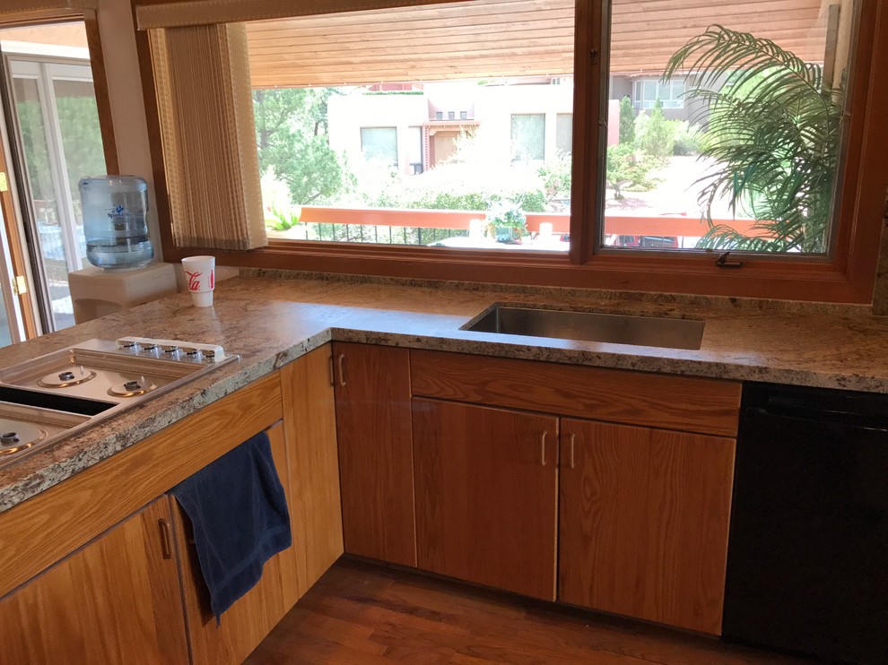 Inspiration for a large transitional l-shaped medium tone wood floor and brown floor eat-in kitchen remodel in Phoenix with a drop-in sink, flat-panel cabinets, medium tone wood cabinets, granite countertops, beige backsplash, stone slab backsplash, stainless steel appliances, a peninsula and beige countertops