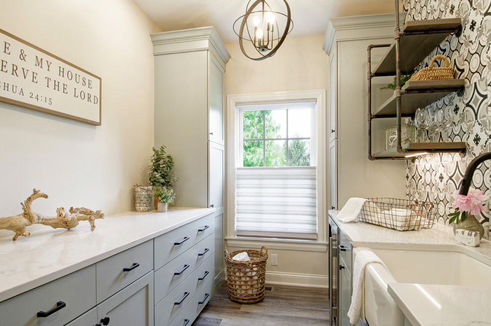 Inspiration for a mid-sized country galley utility room in Columbus with a farmhouse sink, shaker cabinets, grey cabinets, quartzite benchtops, beige walls, vinyl floors, a side-by-side washer and dryer, multi-coloured floor and white benchtop.