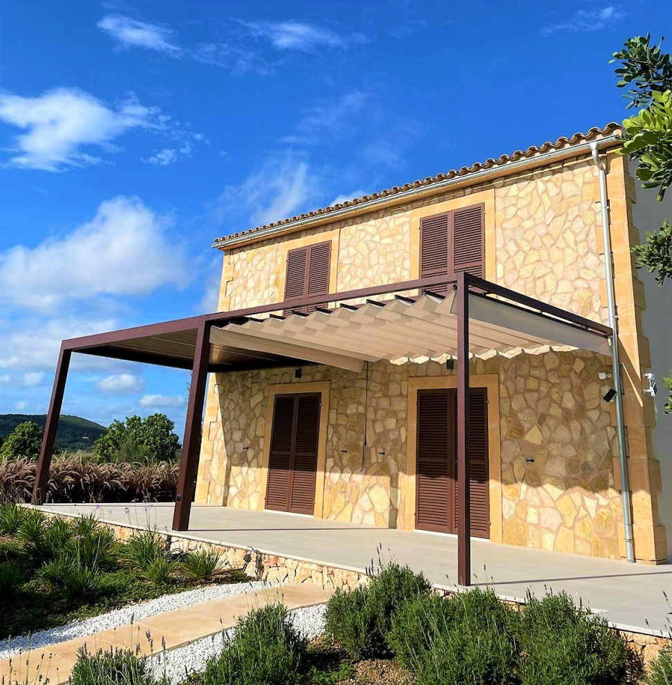 This is an example of a mid-sized country front porch design in Palma de Mallorca with a pergola.