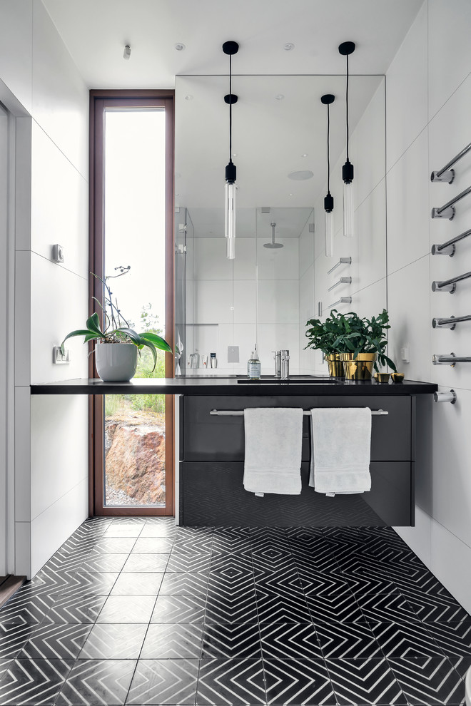 This is an example of a mid-sized contemporary bathroom in Stockholm with white walls, an integrated sink, black floor, black benchtops, flat-panel cabinets, grey cabinets, white tile and mosaic tile floors.