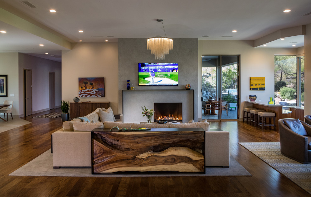 Expansive contemporary open concept living room in Phoenix with beige walls, medium hardwood floors, a concrete fireplace surround, brown floor, a wall-mounted tv and a ribbon fireplace.