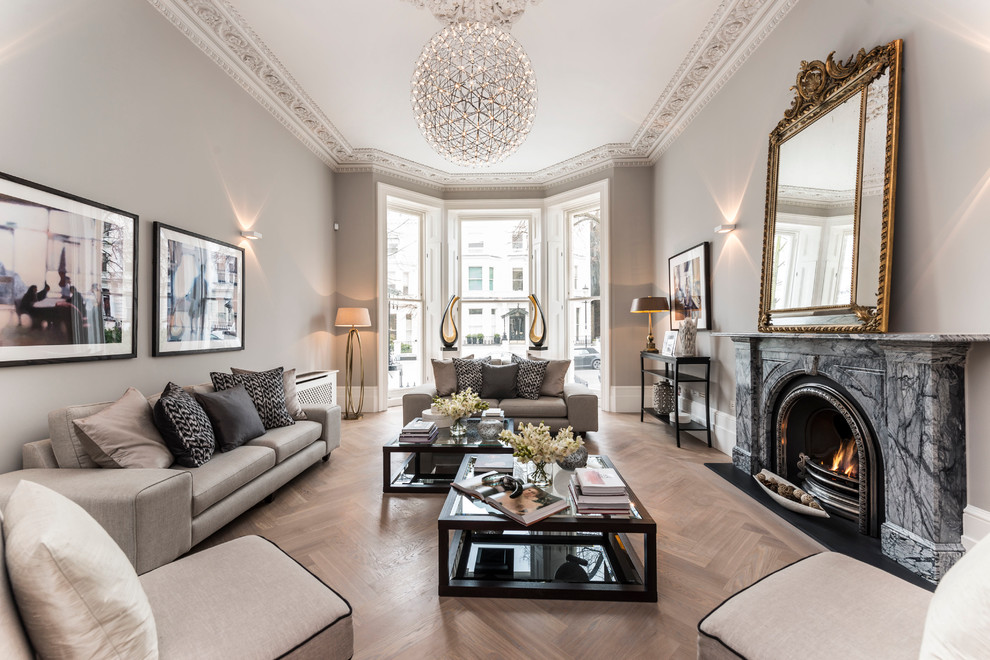 Inspiration for a transitional formal living room in London with beige walls, light hardwood floors, a standard fireplace, a stone fireplace surround and no tv.