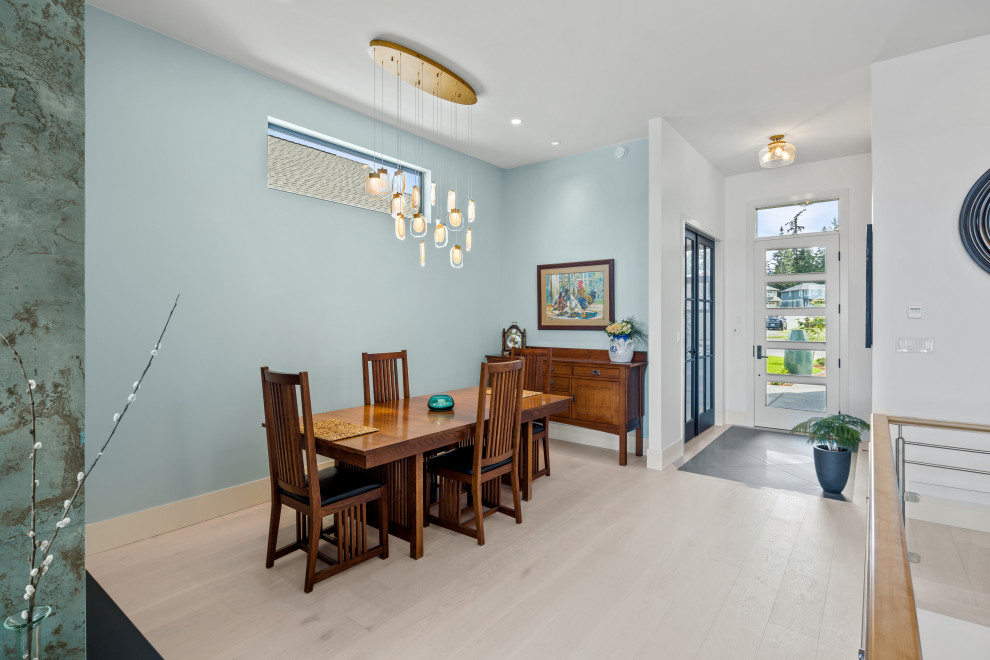 Aménagement d'une salle à manger ouverte sur le salon contemporaine avec un mur bleu, parquet clair, une cheminée ribbon, un manteau de cheminée en carrelage, un sol beige et un plafond voûté.