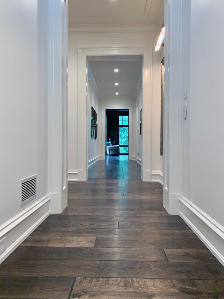 Huge elegant dark wood floor and brown floor hallway photo in Chicago with white walls