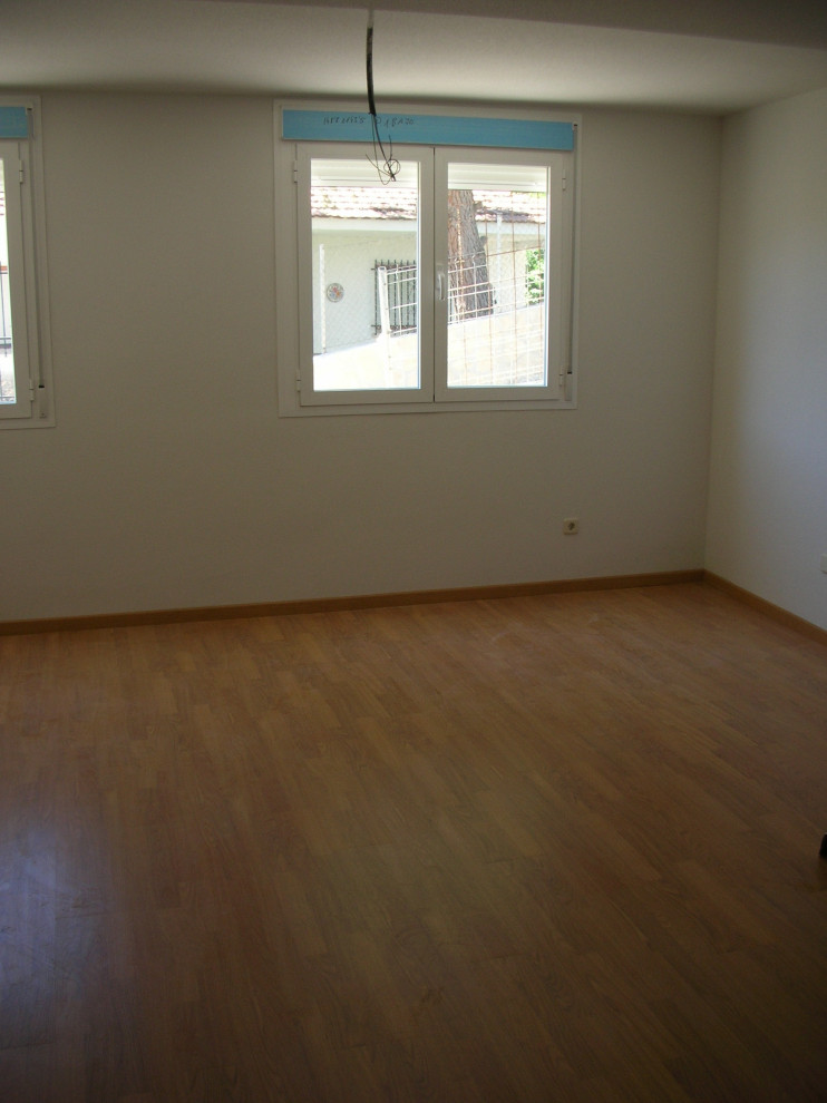 This is an example of a large modern enclosed living room in Other with white walls, medium hardwood floors and brown floor.