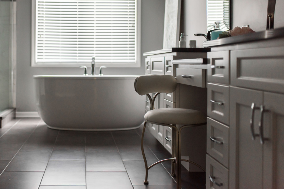 Example of a mid-sized transitional master white tile and porcelain tile porcelain tile, gray floor, double-sink and vaulted ceiling freestanding bathtub design in Chicago with shaker cabinets, white cabinets, a two-piece toilet, gray walls, an undermount sink, solid surface countertops, gray countertops and a built-in vanity
